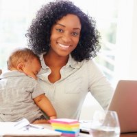 Mother holding baby while doing schoolwork