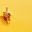 A "thumbs up" bursting through a yellow background