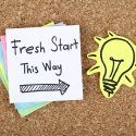 Bulletin board with sticky note that reads "Fresh start this way"