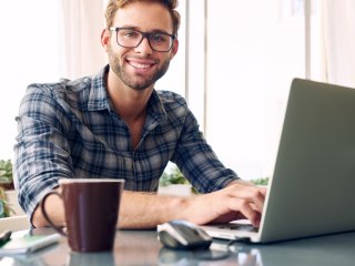 Male student at laptop smiling at camera