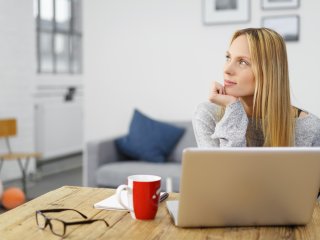 Working female looking distractedly away from her laptop