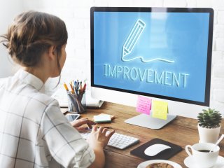 Woman in front of computer with "improvement" written on the screen